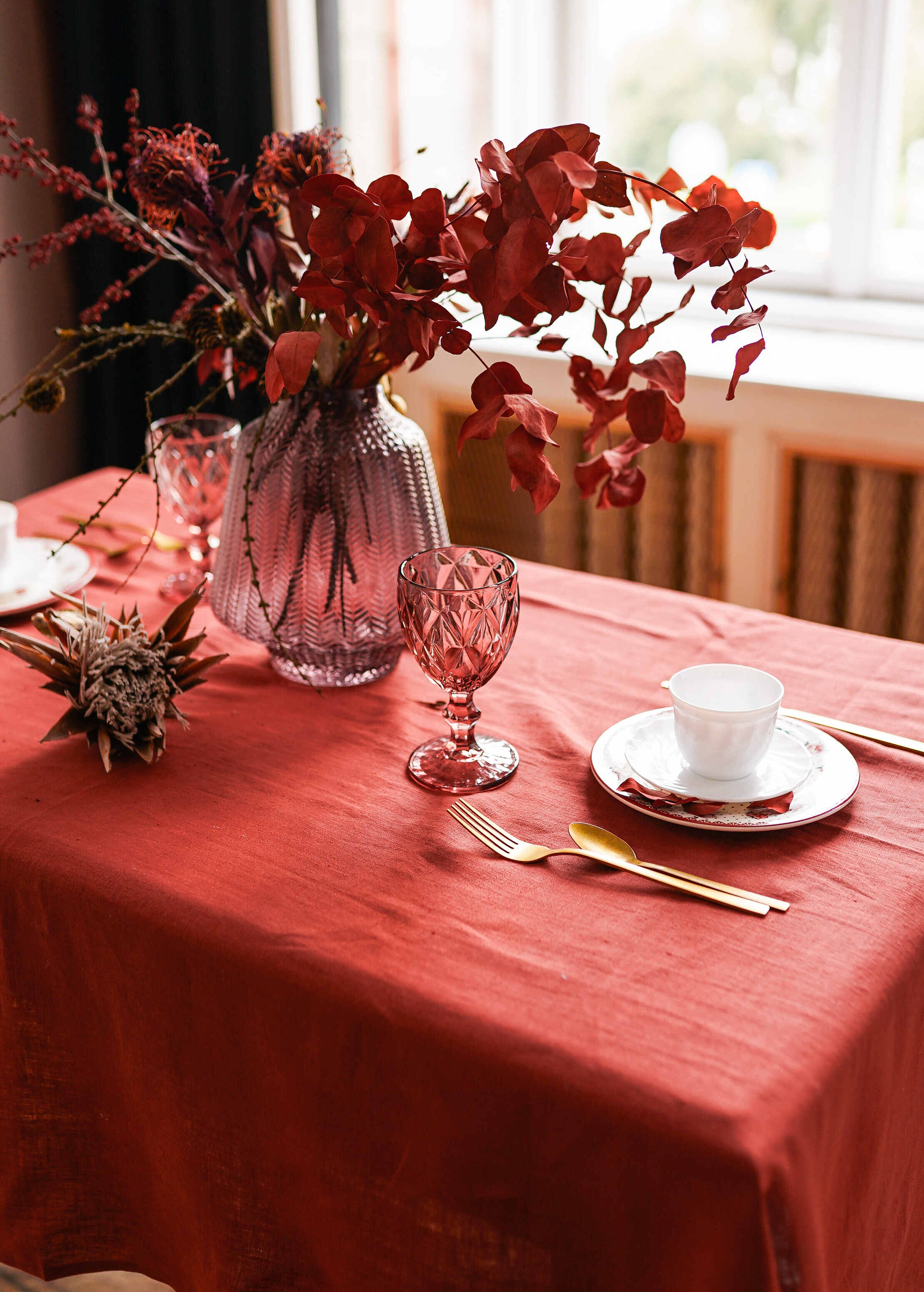a table with a red table cloth and a vase with red flowers