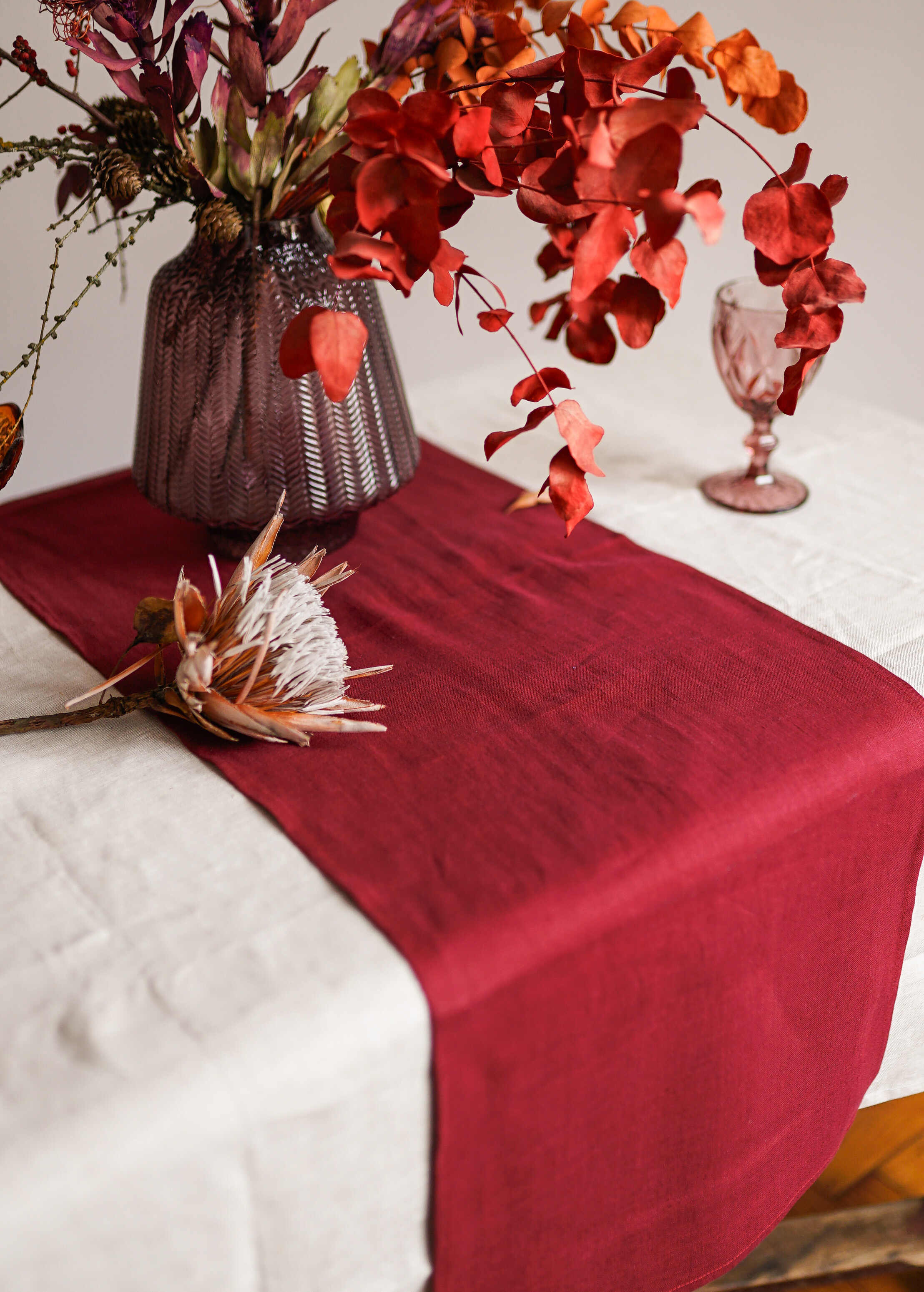 a vase of flowers on a table with a red table runner
