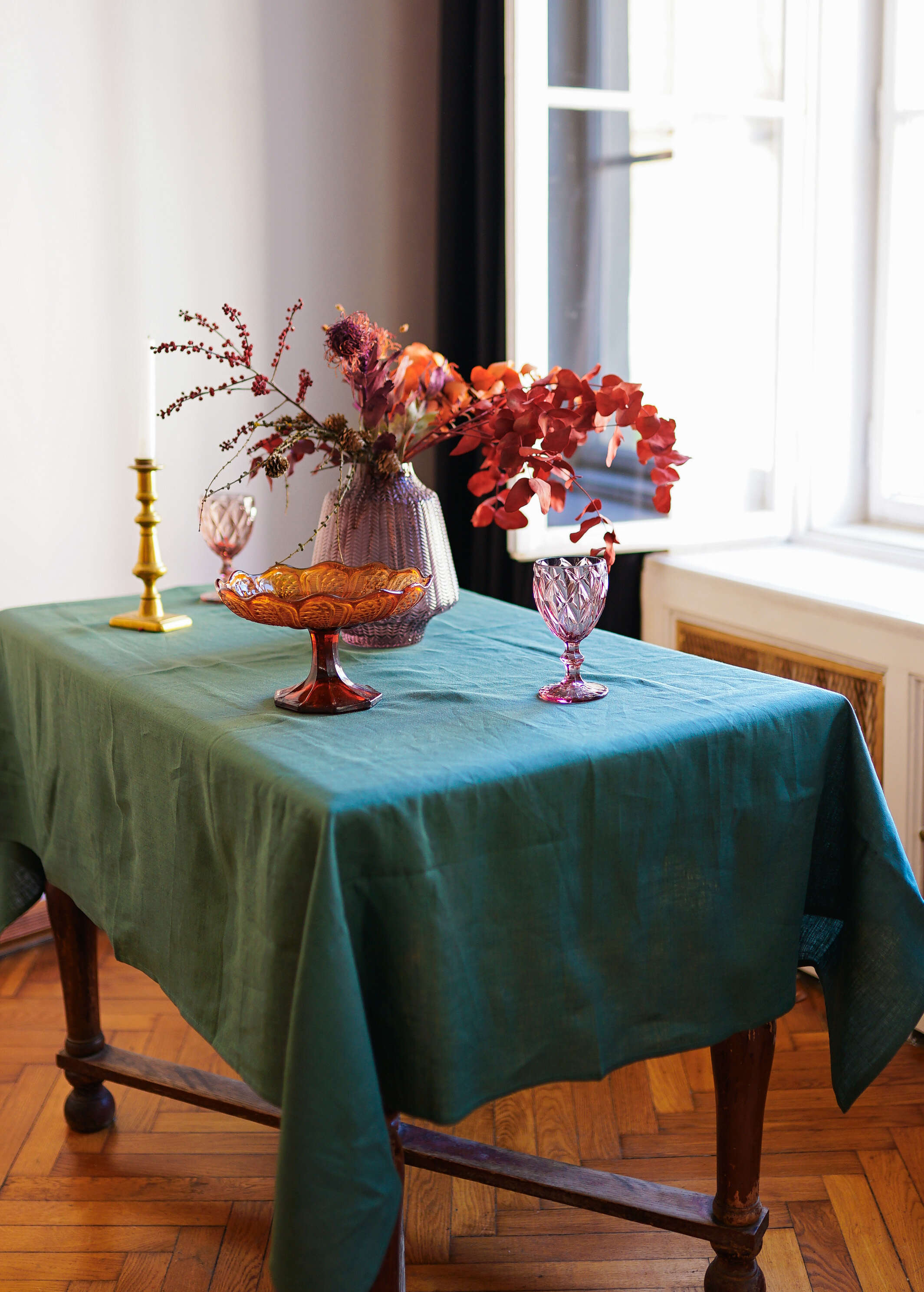 a table with a green table cloth and vases on it