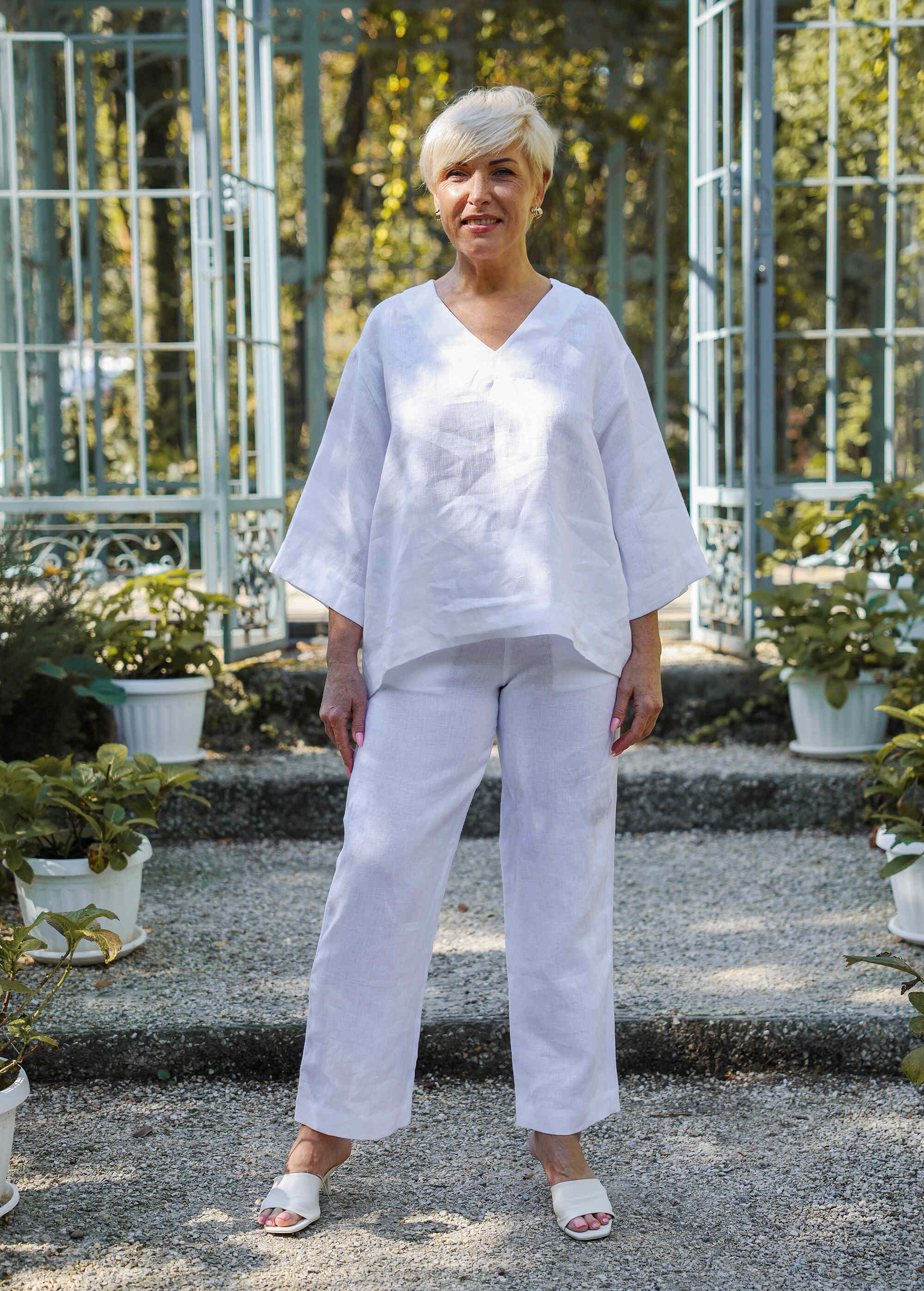 a woman standing in front of some potted plants